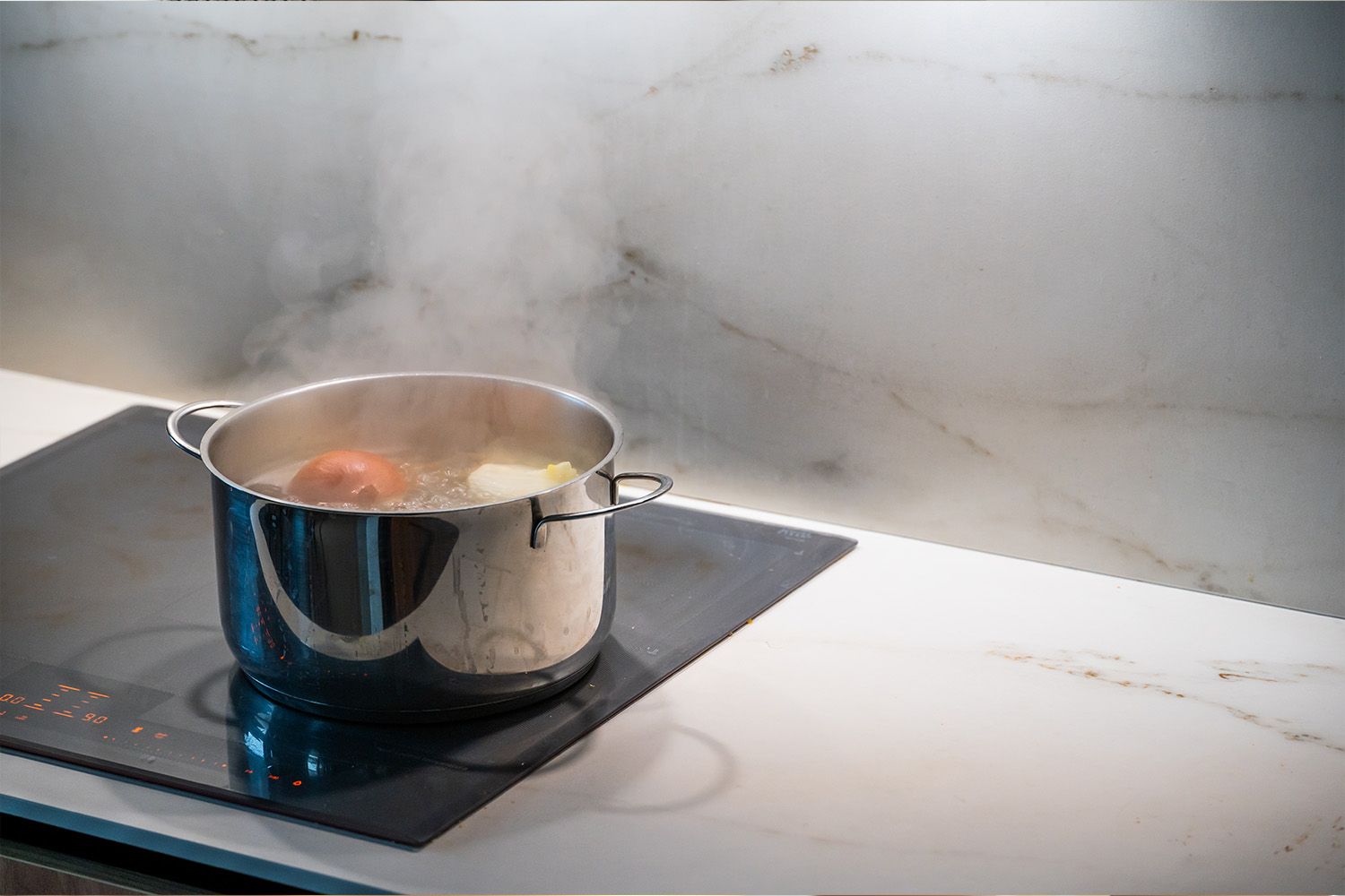 Matlagning på spisen under en fungerande köksfläkt.