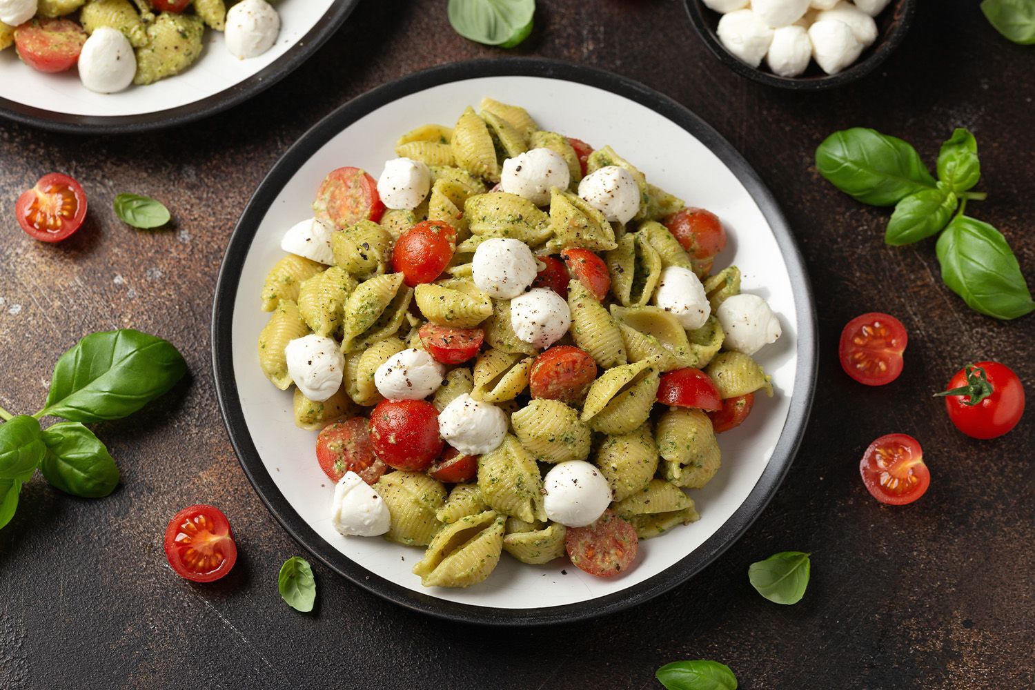 Bild på en pasta-pesto sallad med tomat och ost.